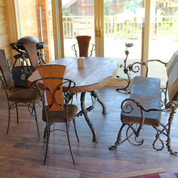Hand-wrought iron dining table in a combination with oak wood, wrought iron chairs and a leather upholstered bench Hand-wrought iron dining table in a combination with oak wood, wrought iron chairs and a leather upholstered bench