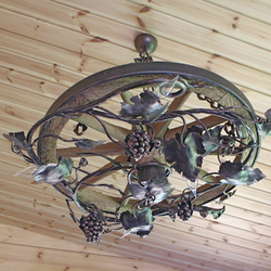 An exceptional hand wrought chandelier of a vine design is forged into the wagon wheel An exceptional hand wrought chandelier of a vine design is forged into the wagon wheel
