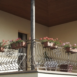 Kované zábradlie na balkóne rodinného domu s držiakmi kvetináčov Kované zábradlie na balkóne rodinného domu s držiakmi kvetináčov
