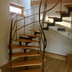 Točité kované schodisko so zábradlím doplnené lanom v interiéri rodinného domu na východe Slovenska